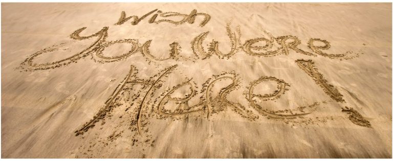 holiday special Text written in the sand saying "Wish you were here!"